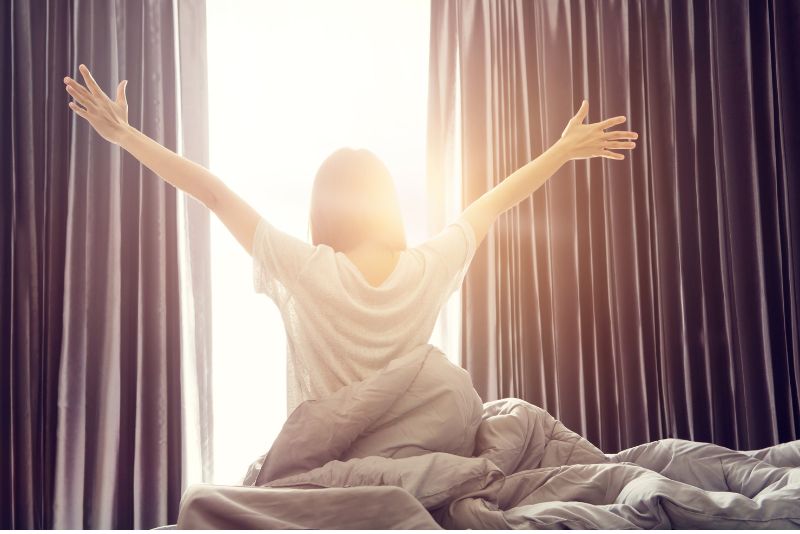 woman facing window stretching arms